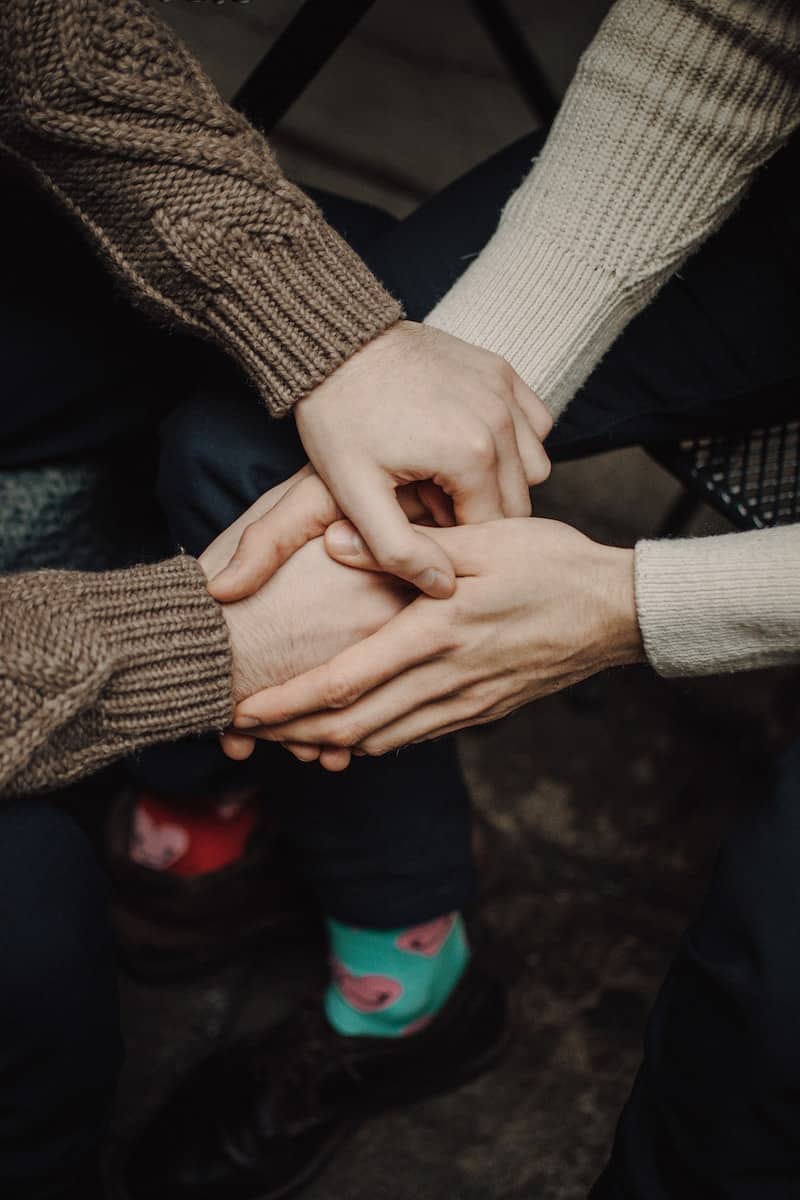 person in gray sweater holding hands of person in black long sleeve shirt